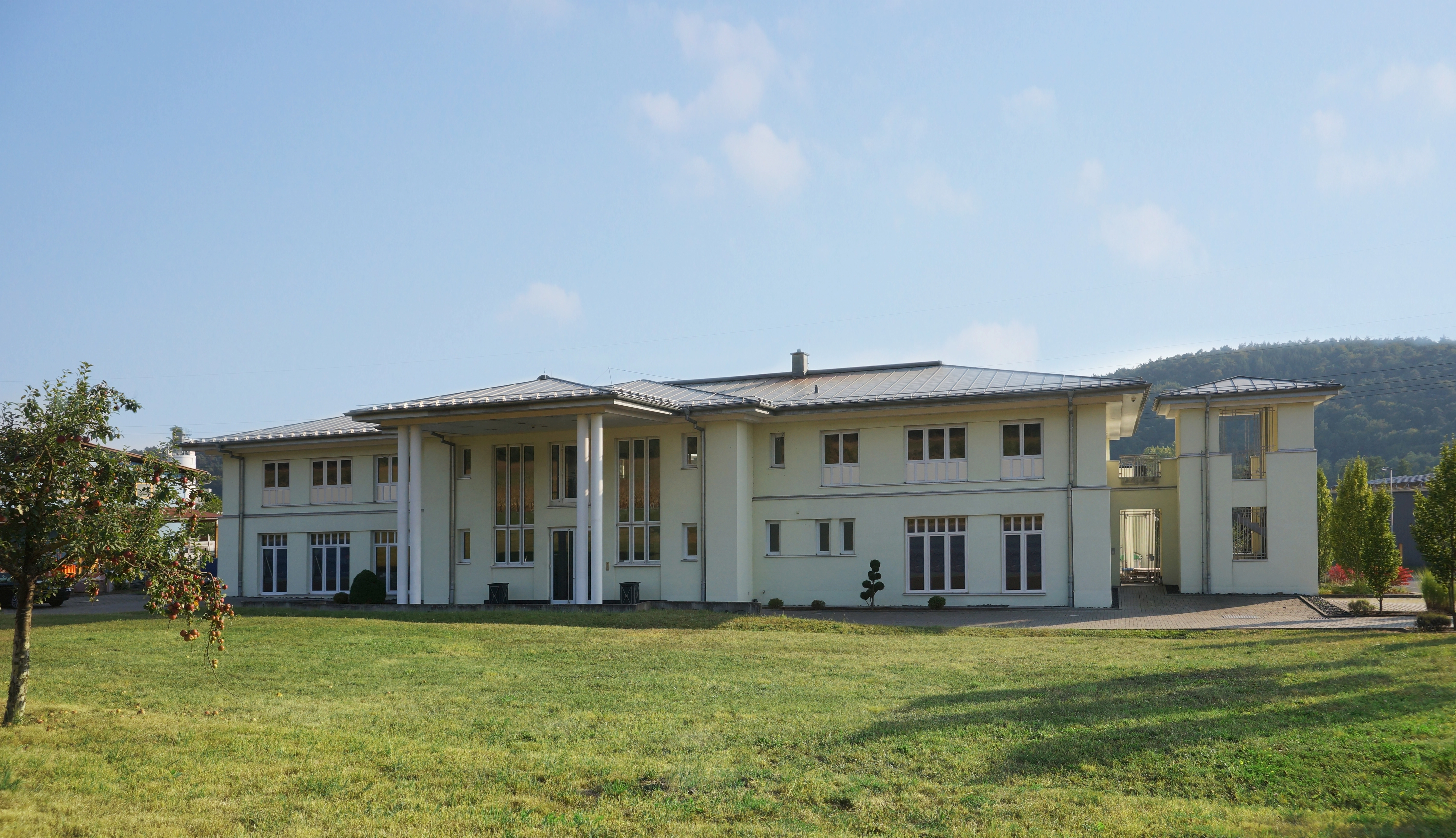 Zweistöckiges, modernes Firmengebäude mit hellgelber Fassade und großen Fenstern